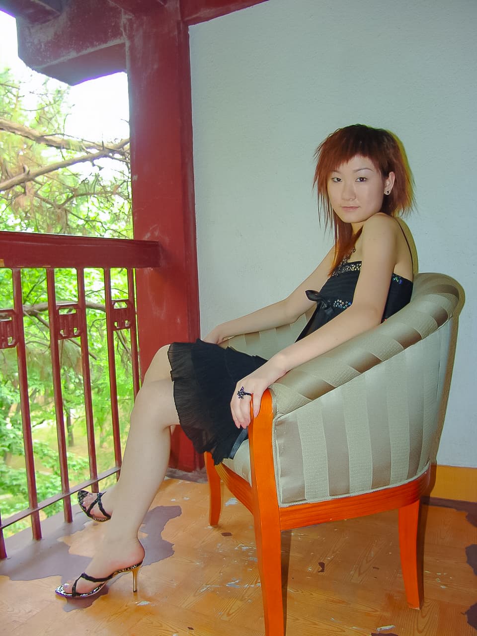 Fangfei balancing on the ball of her foot in strappy heeled sandals, arch pronounced, nylon sheen visible near the ankle